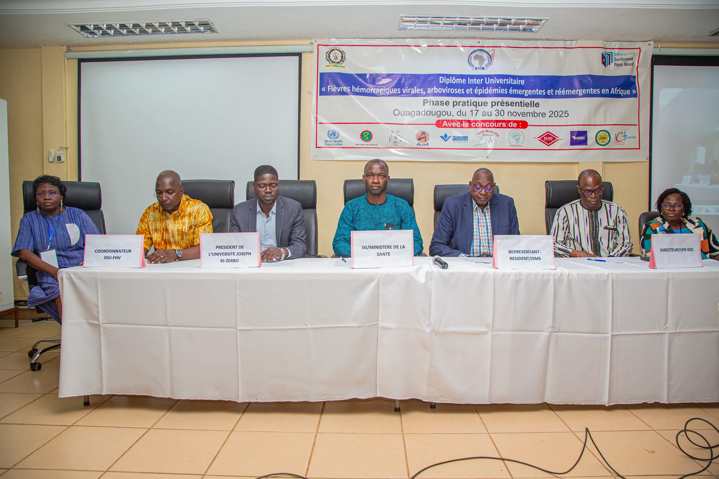 Cérémonie d'ouverture de la phase pratique du Diplôme interuniversitaire « Fièvres hémorragiques virales, arboviroses, épidémies émergentes et réémergentes en Afrique », Ouagadougou, novembre 2025 : les officiels assis derrière une table, la banderole du DIU au mur.