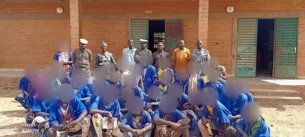Personnes détenues en uniforme bleu réunies dans la cour d'une maison d'arrêt, visages floutés.